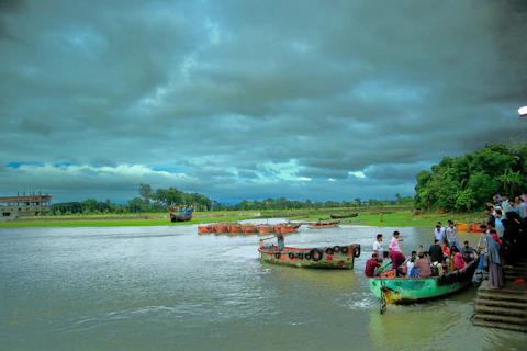 a group of people standing on the side of a river next to boats