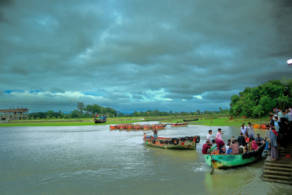 a group of people standing on the side of a river next to boats