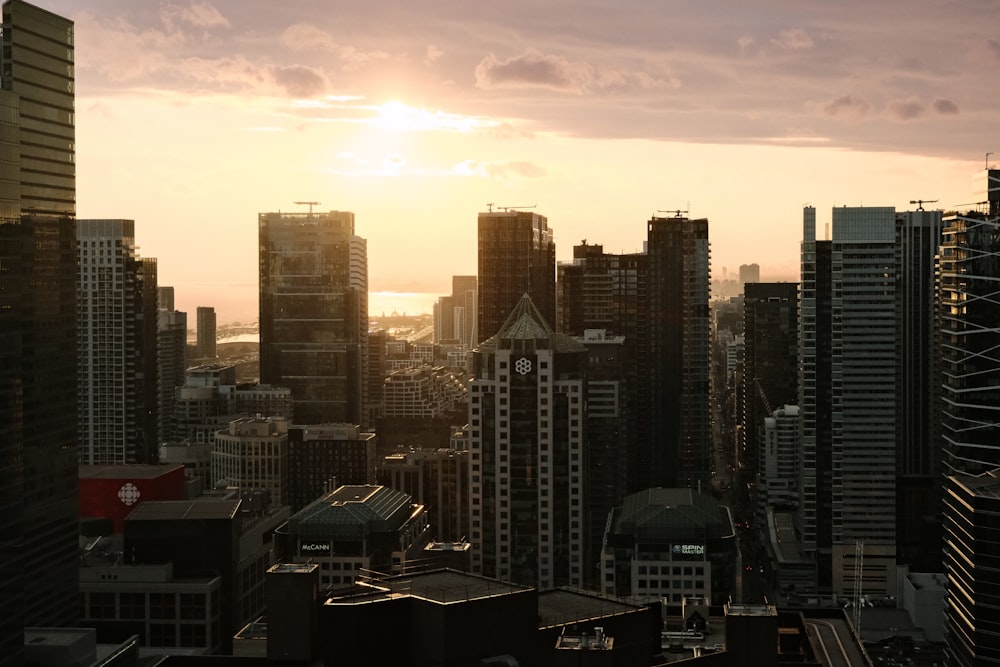 the sun is setting over a city with tall buildings