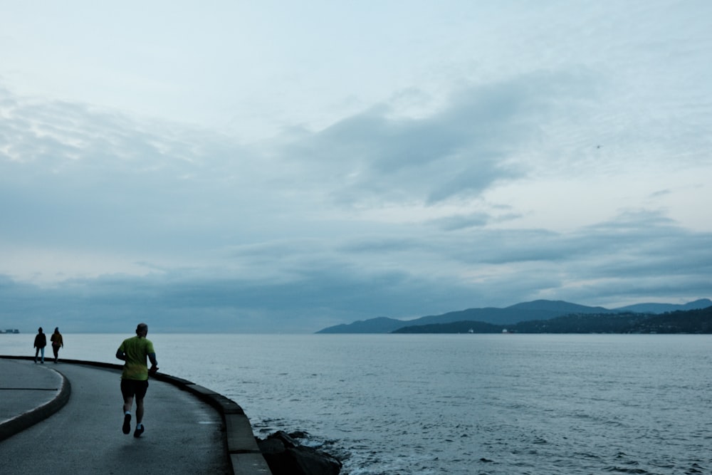 a man running along a road next to a body of water