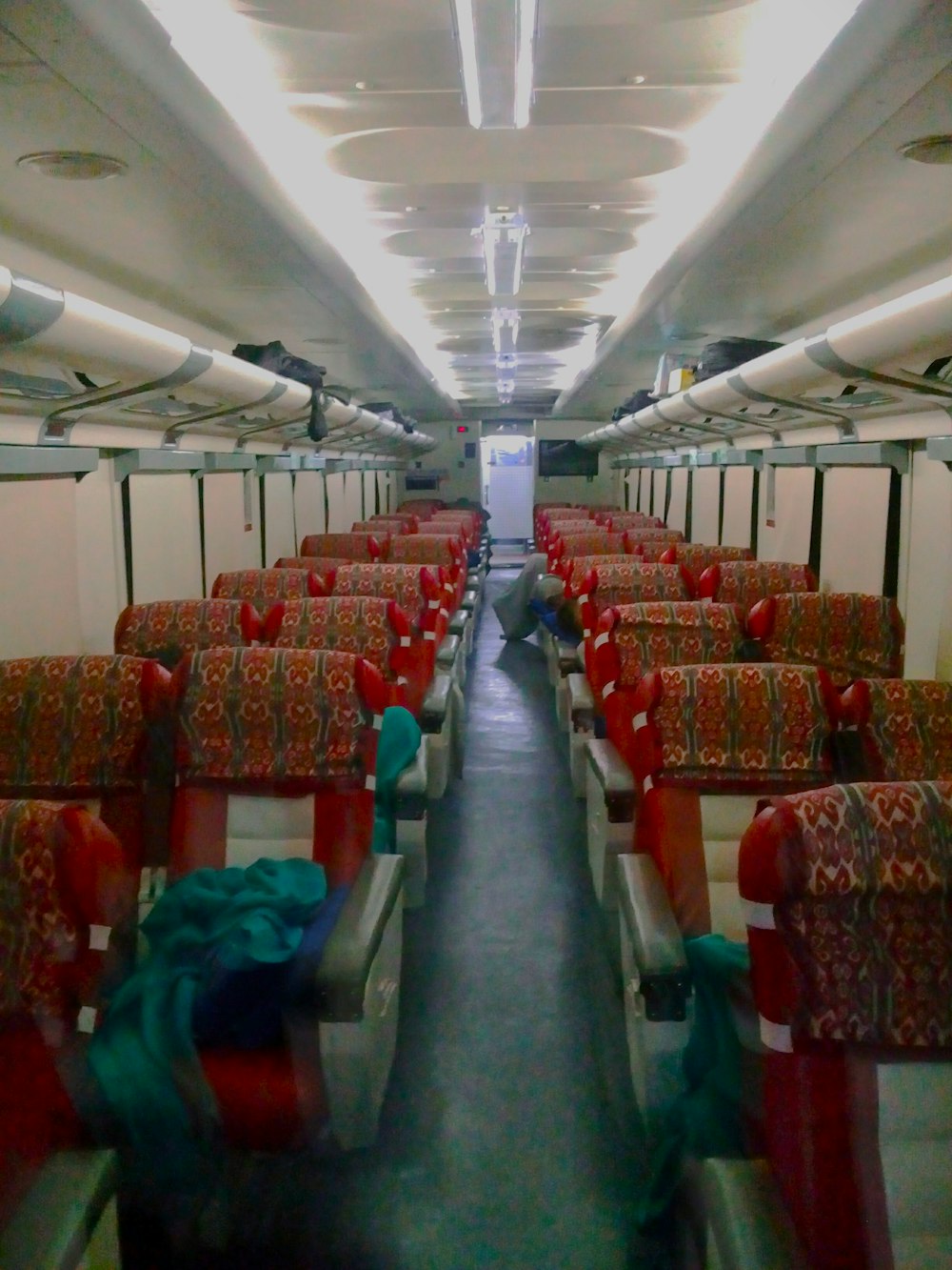 an empty train car with red seats and colorful blankets