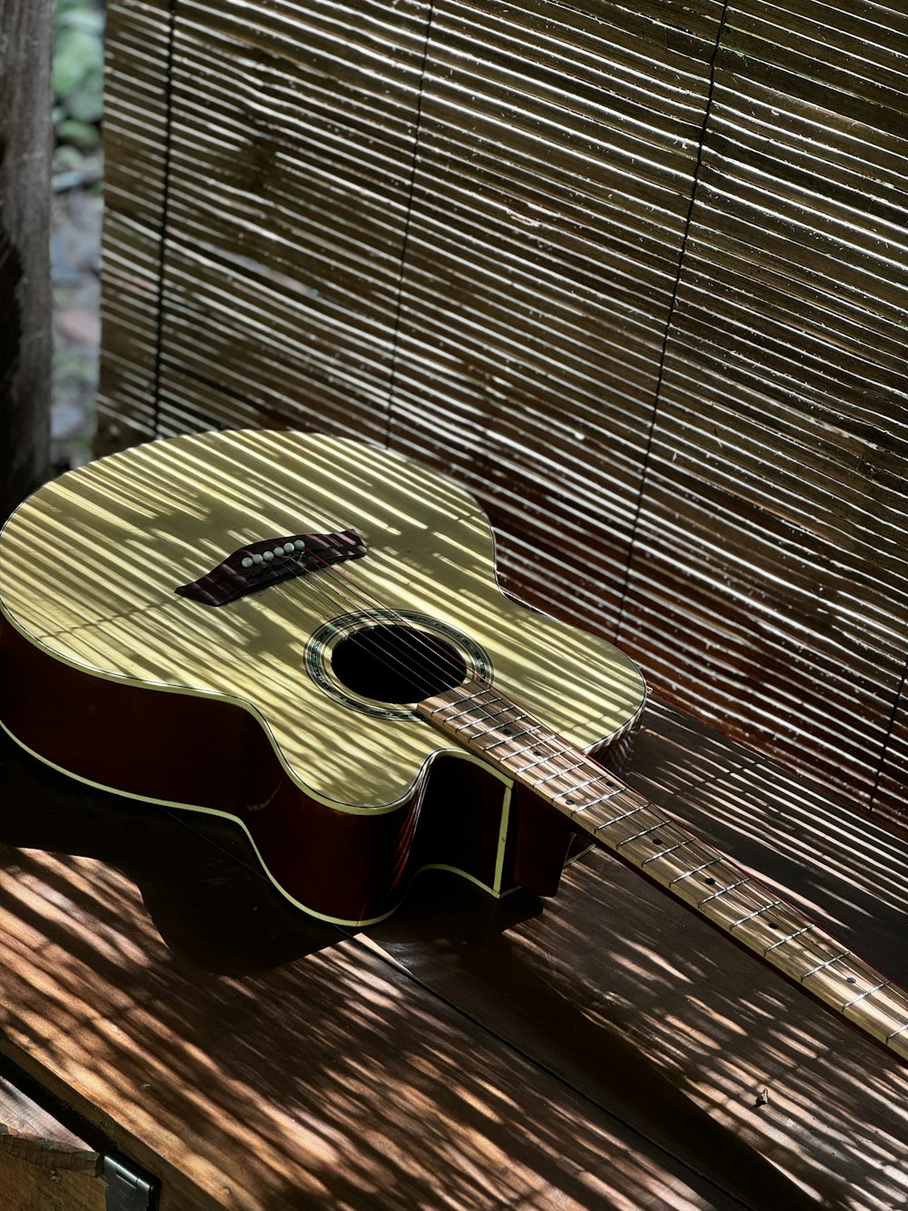 an acoustic guitar sitting on a wooden bench