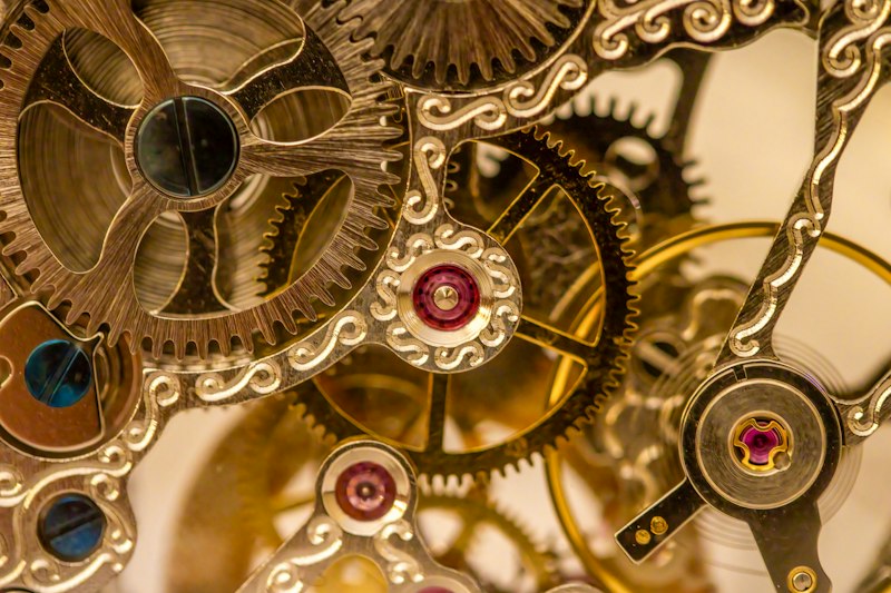 Detail of a clock dial with visible gearing behind it, echoing the ring-and-pointer dials of the Antikythera Mechanism