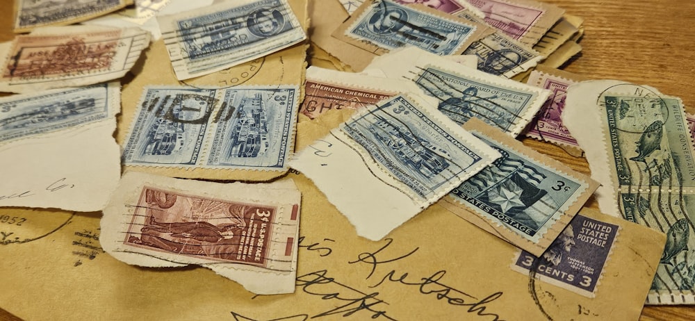 a pile of old postage sitting on top of a wooden table