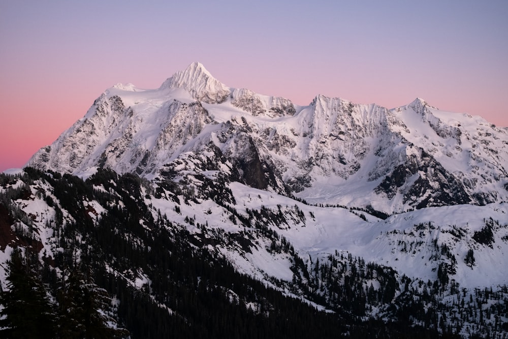 a snow covered mountain with a pink sky