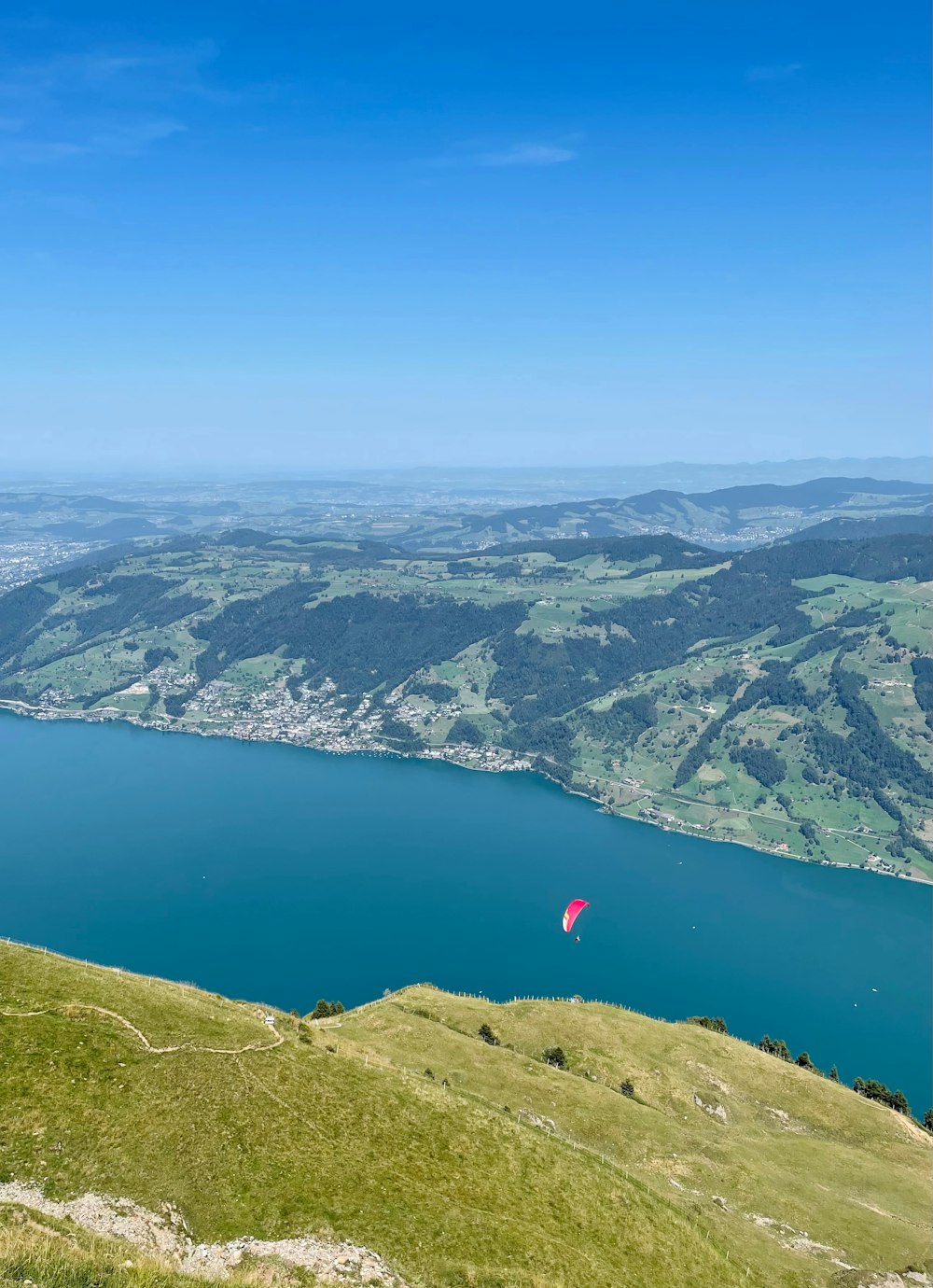 a person flying a kite on top of a lush green hillside