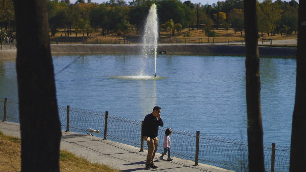 a man and a little girl walking by a pond