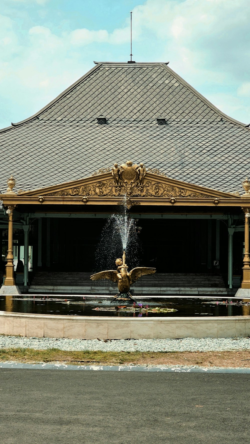 a fountain in front of a building with a sky background