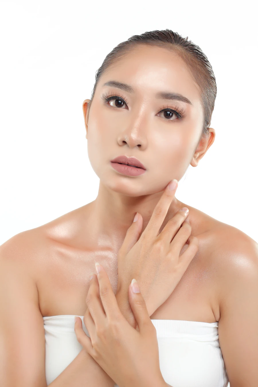 Portrait of a woman in a white top resting her hands near her collarbone
