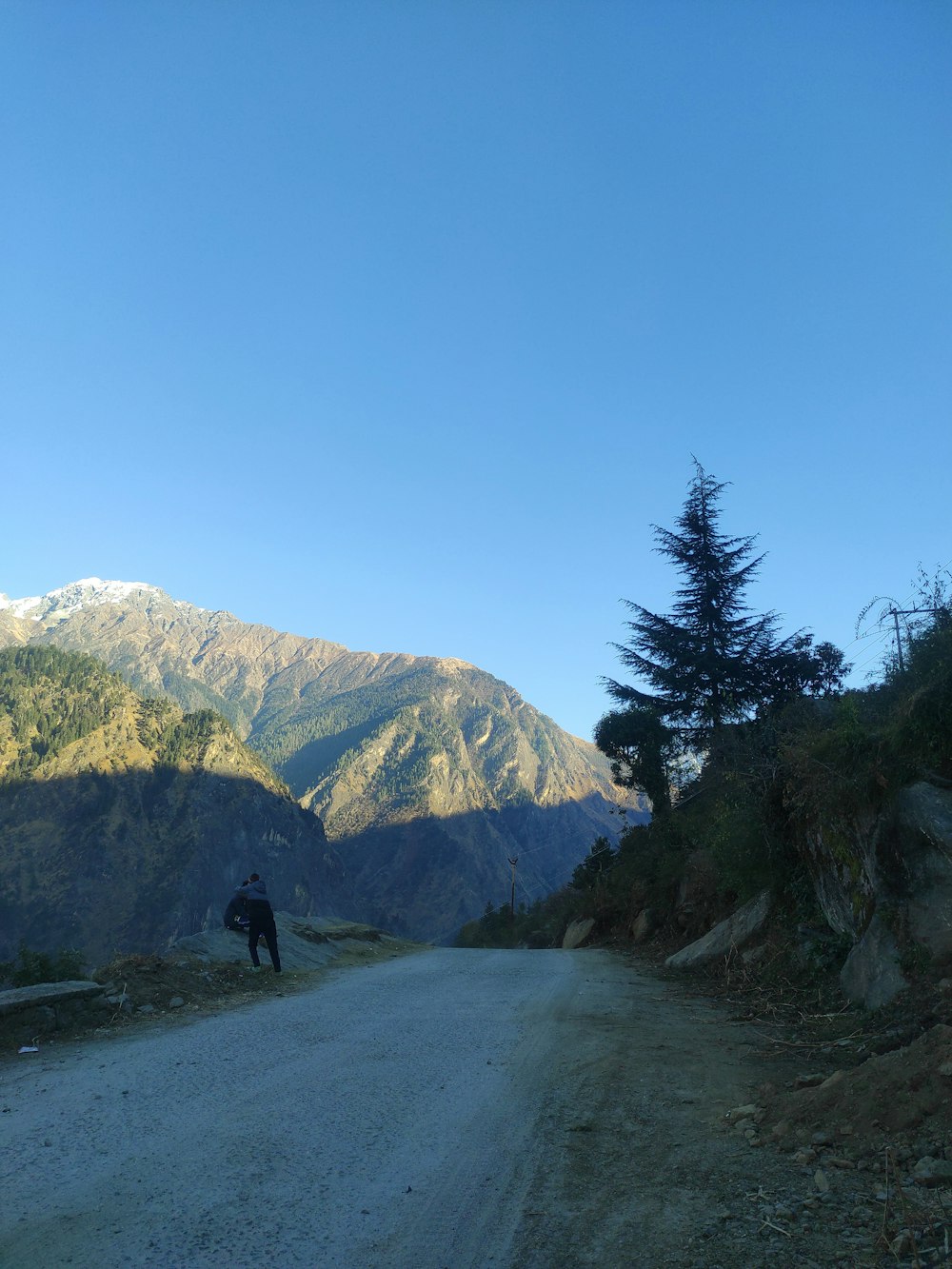 a person standing on a dirt road in front of mountains