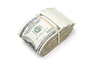 a stack of one hundred dollar bills tied with a string