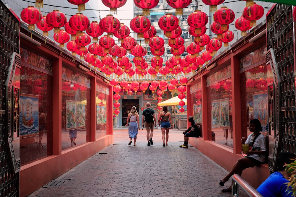 a group of people walking down a street under red lanterns