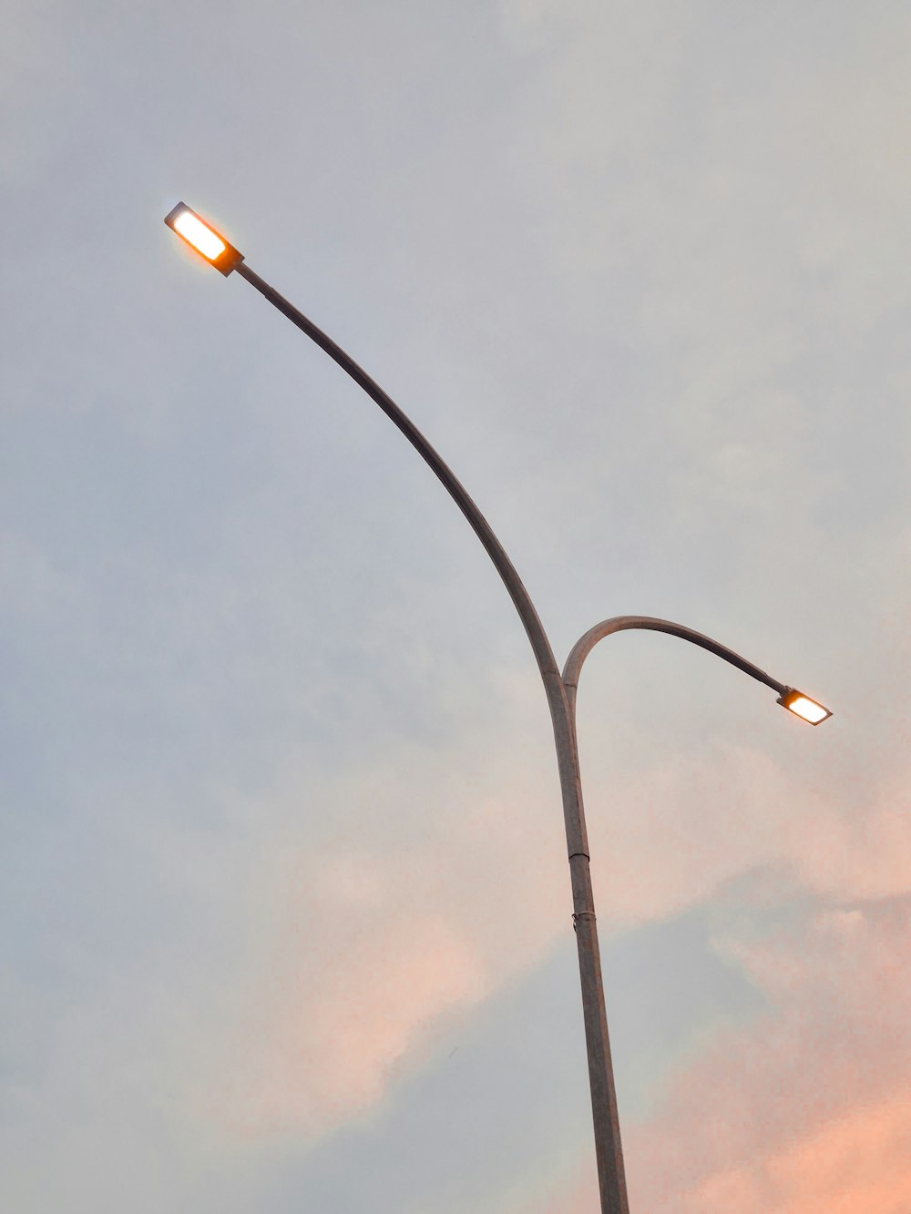 a street light on a pole with a cloudy sky in the background