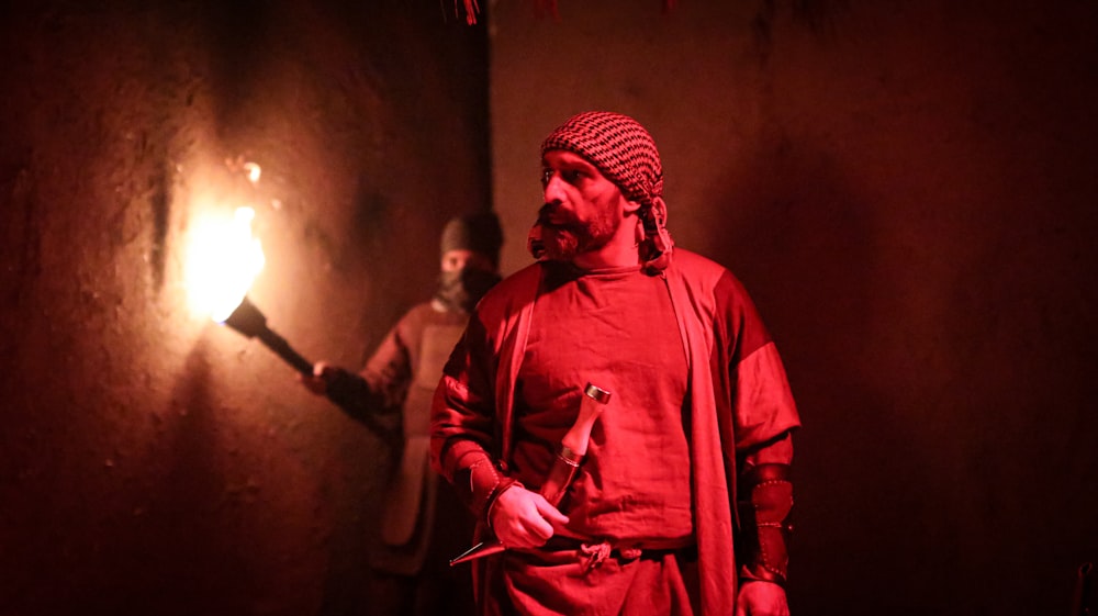 a man in a red outfit holding a lit candle