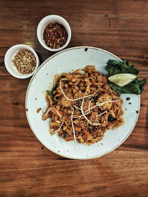 A white plate topped with noodles and meat