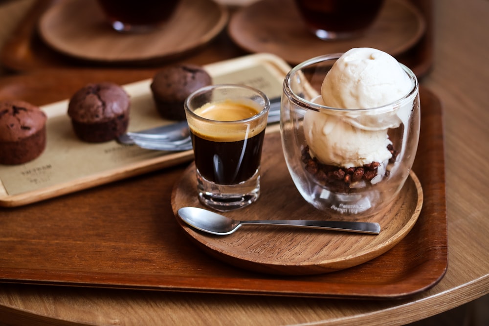 a wooden tray topped with a glass of ice cream