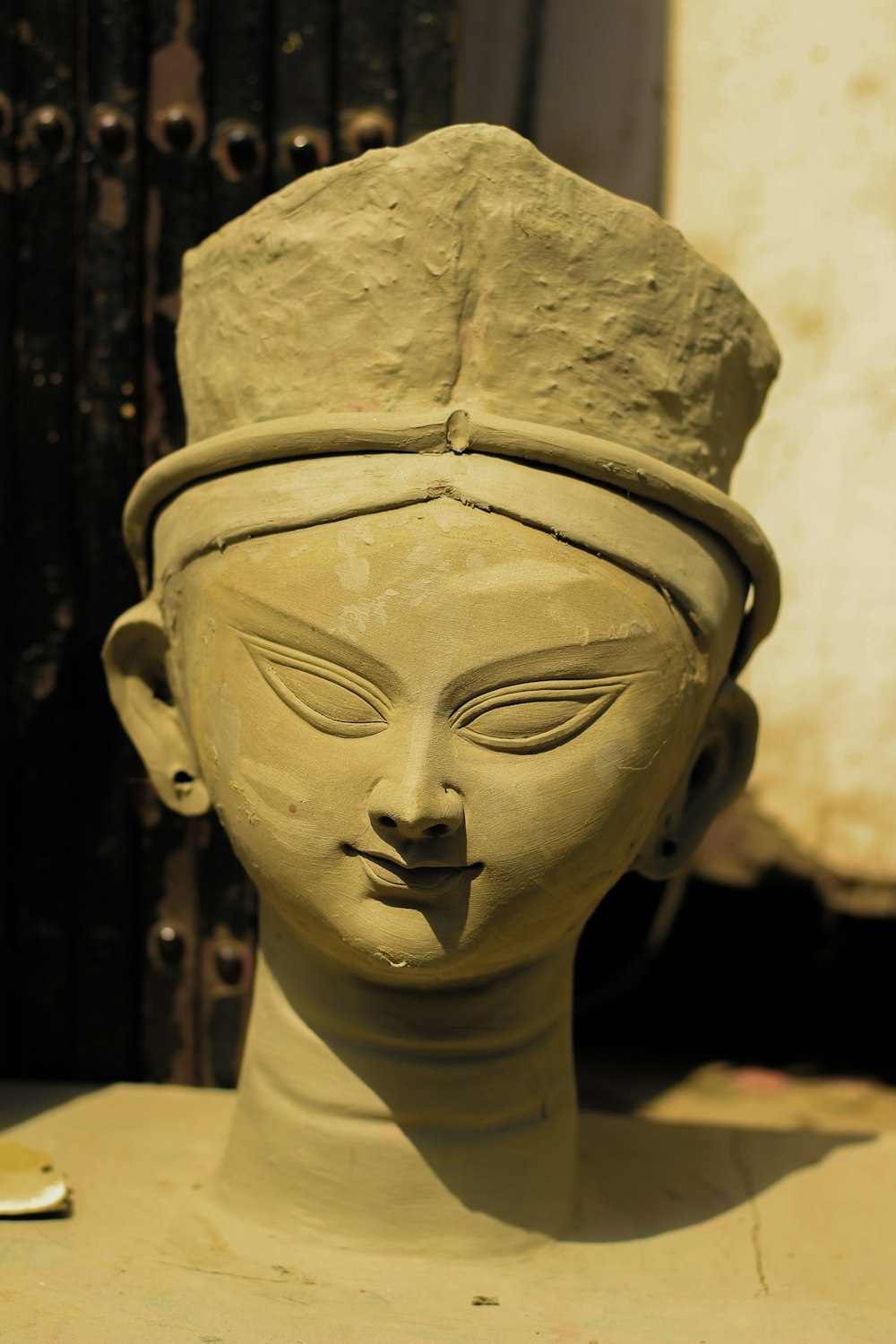 a clay sculpture of a woman's head wearing a hat