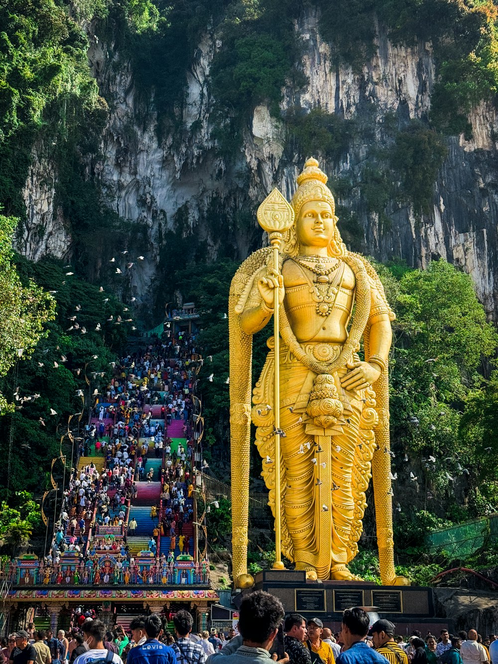 a large statue of a man holding a spear in front of a crowd of people