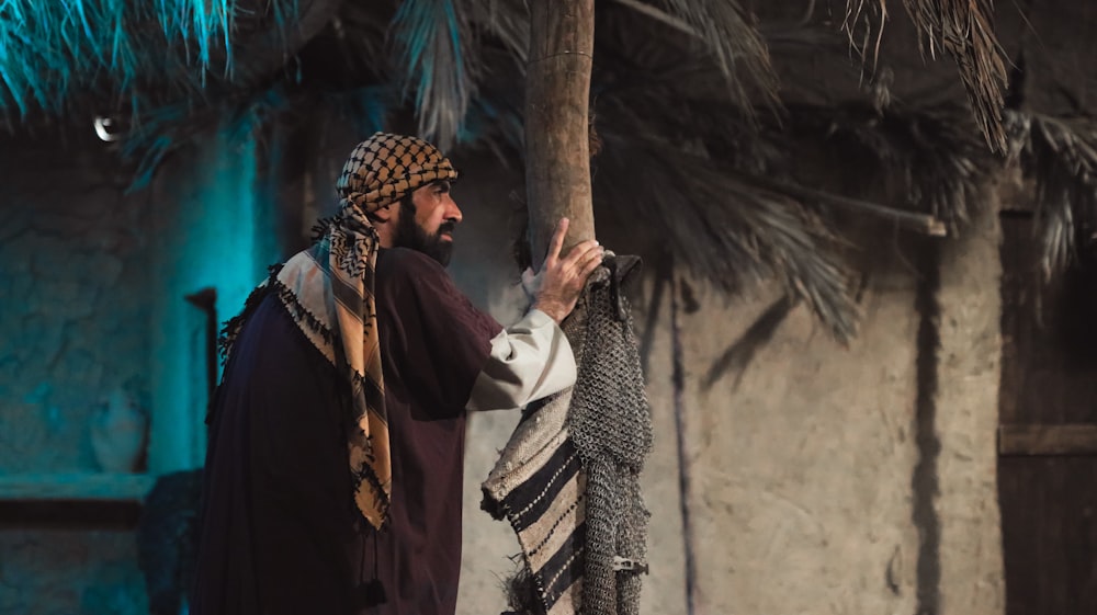 a man dressed in traditional clothing holding a palm tree