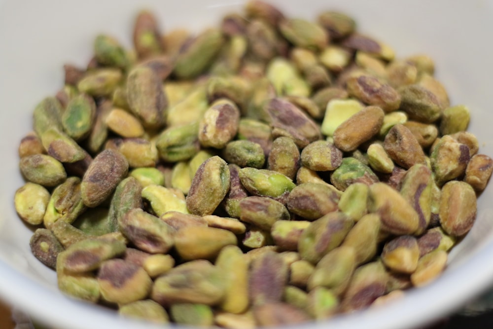 a white bowl filled with pistachios on top of a table