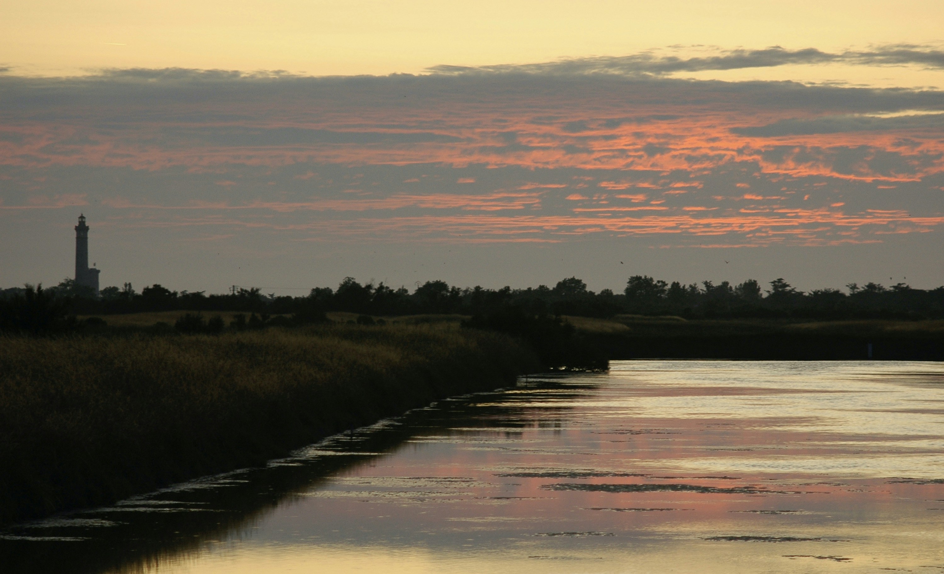 a body of water with a light house in the distance