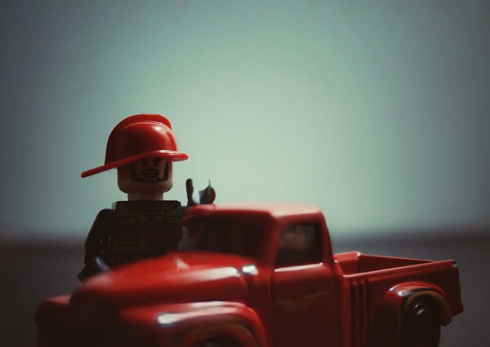 a red toy truck with a fireman standing next to it