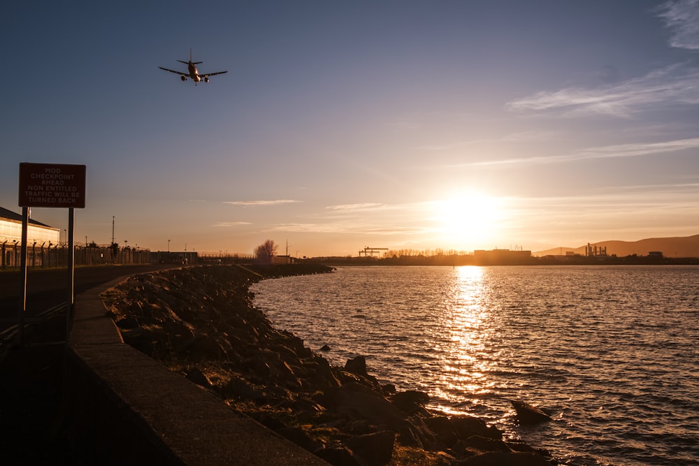 a plane flying over a body of water at sunset