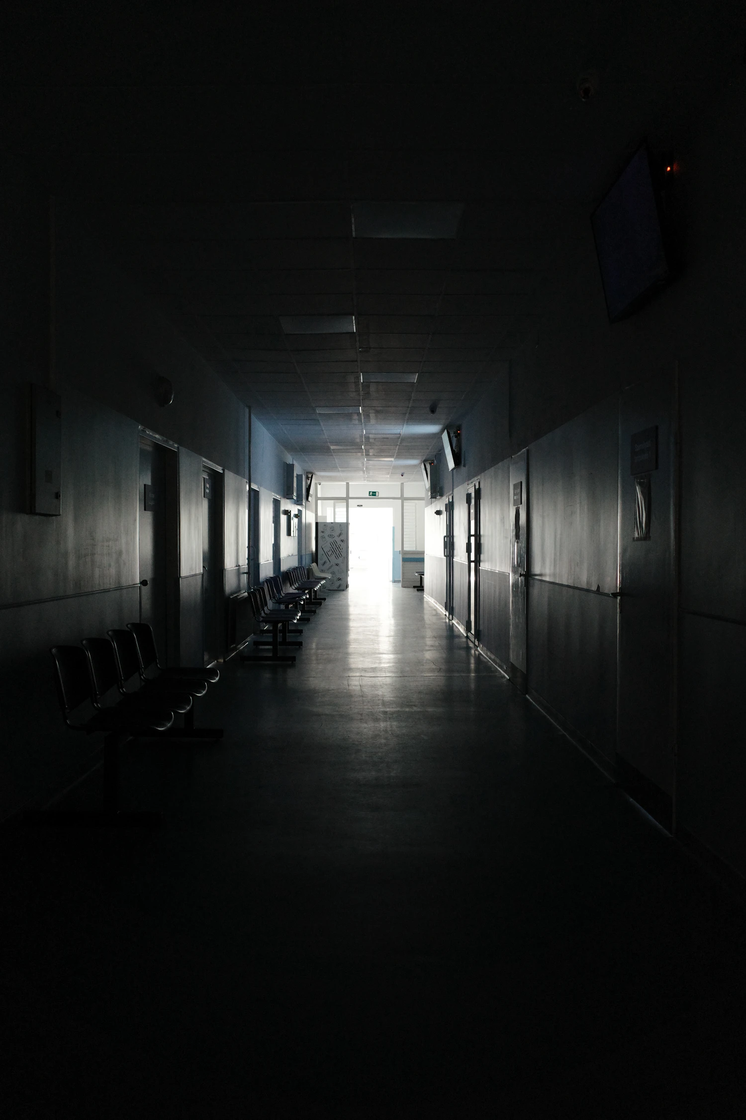 A long, quiet hospital corridor at night with light at the far end