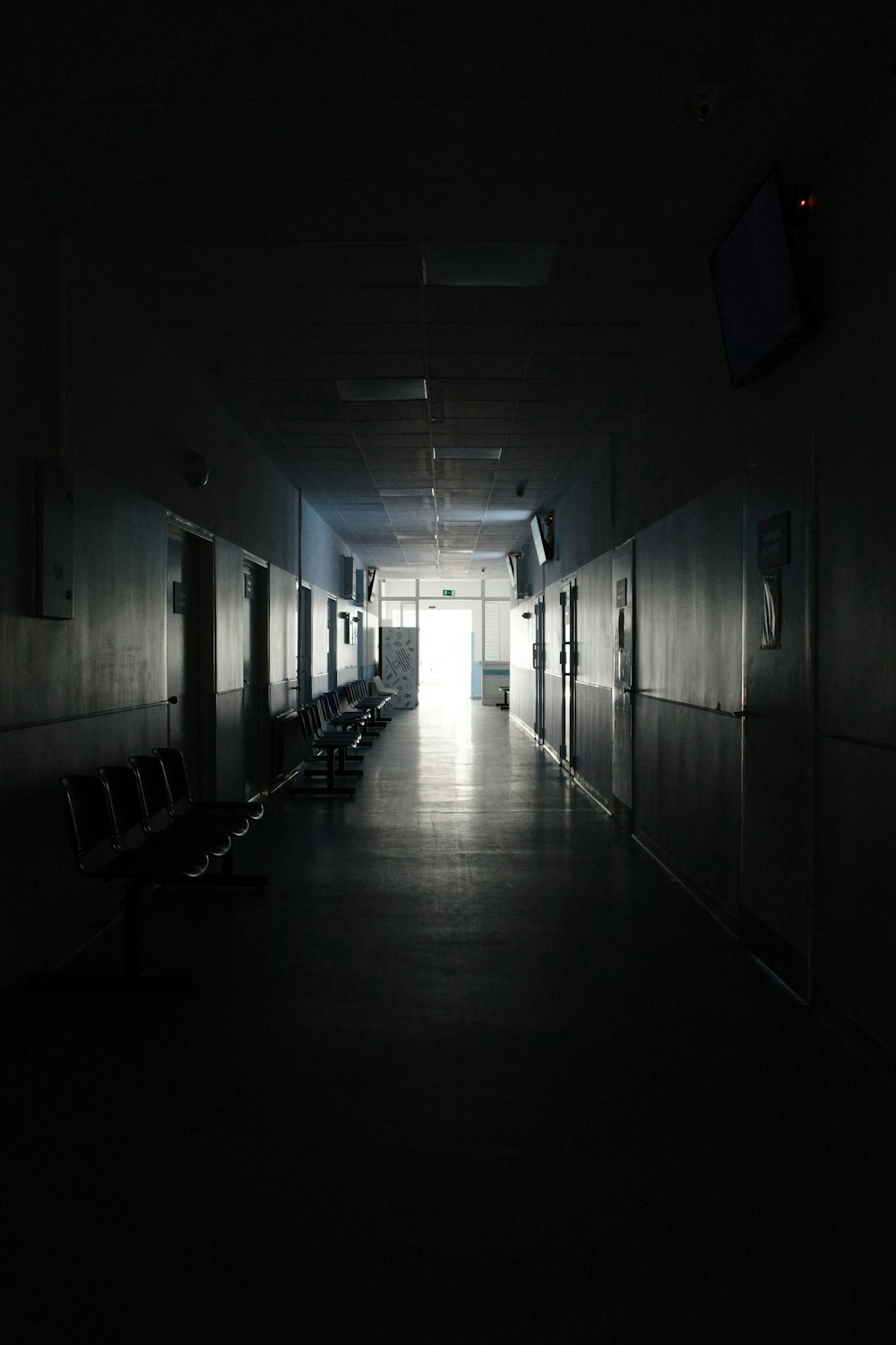 a dark hallway with benches and a television on the wall
