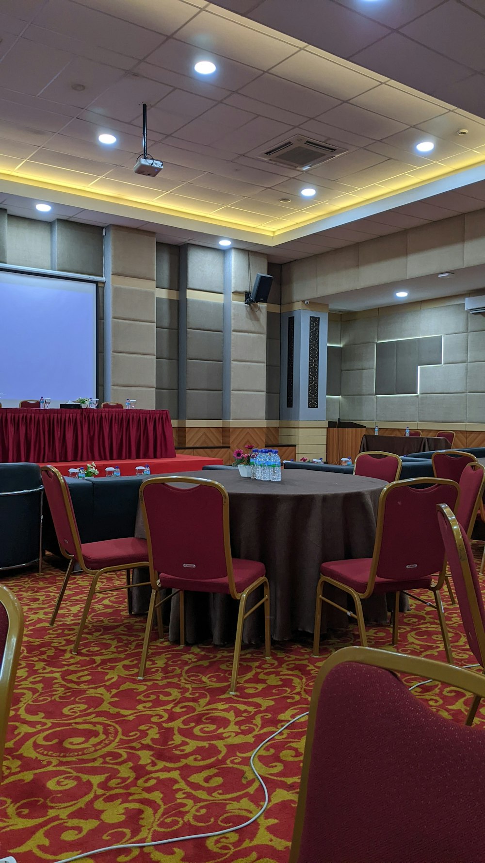una sala conferenze con schermo per proiettori e sedie