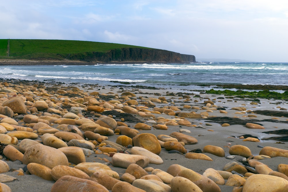 a beach covered in lots of rocks next to the ocean