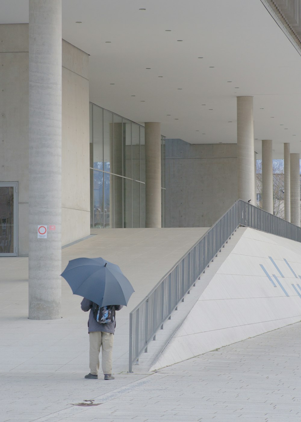 uma pessoa com um guarda-chuva em pé em frente a um prédio