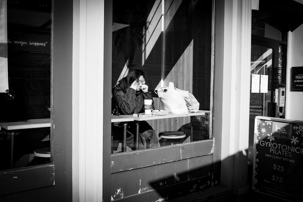 a woman sitting at a table with a dog in front of her