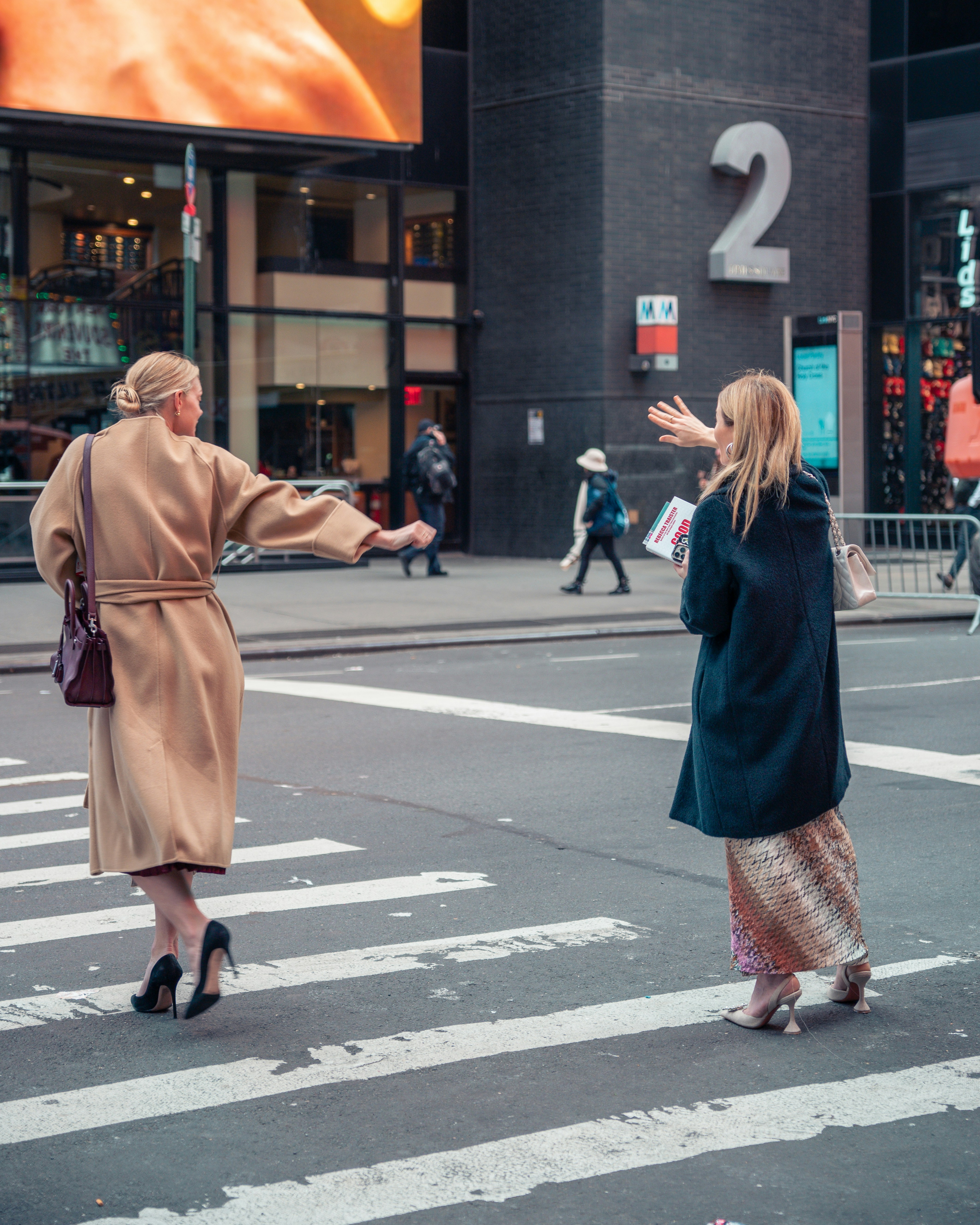 two women standing on the side of a street