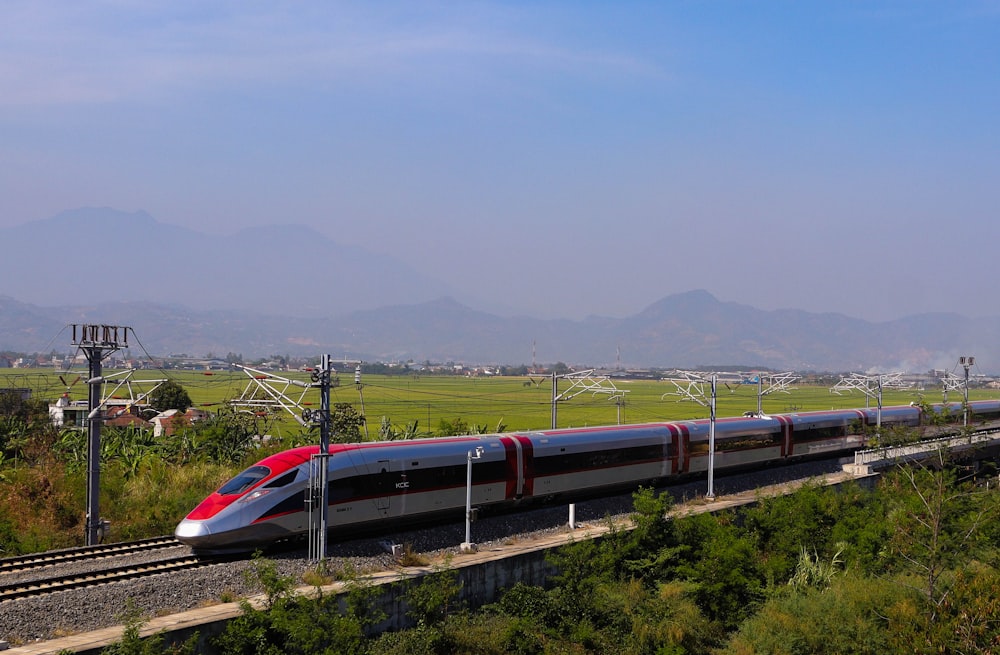 um trem vermelho e prateado viajando pelos trilhos do trem