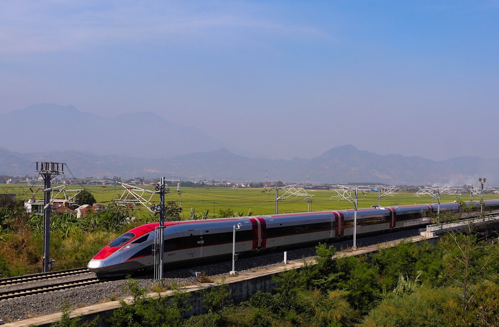 a red and silver train traveling down train tracks