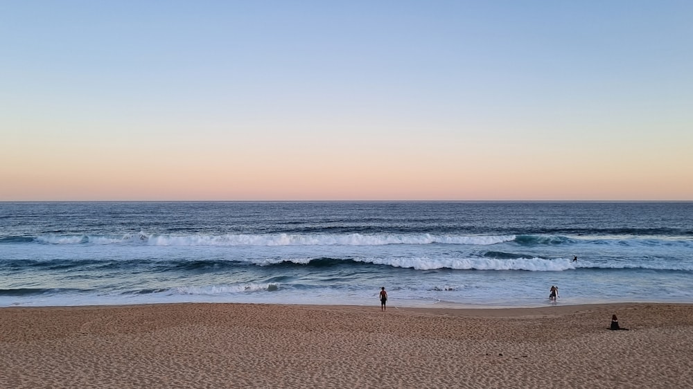 a couple of people standing on top of a sandy beach