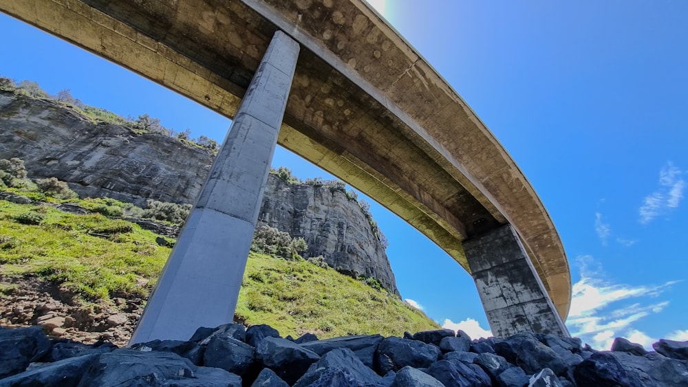 a view of a bridge over rocks with a rainbow in the sky