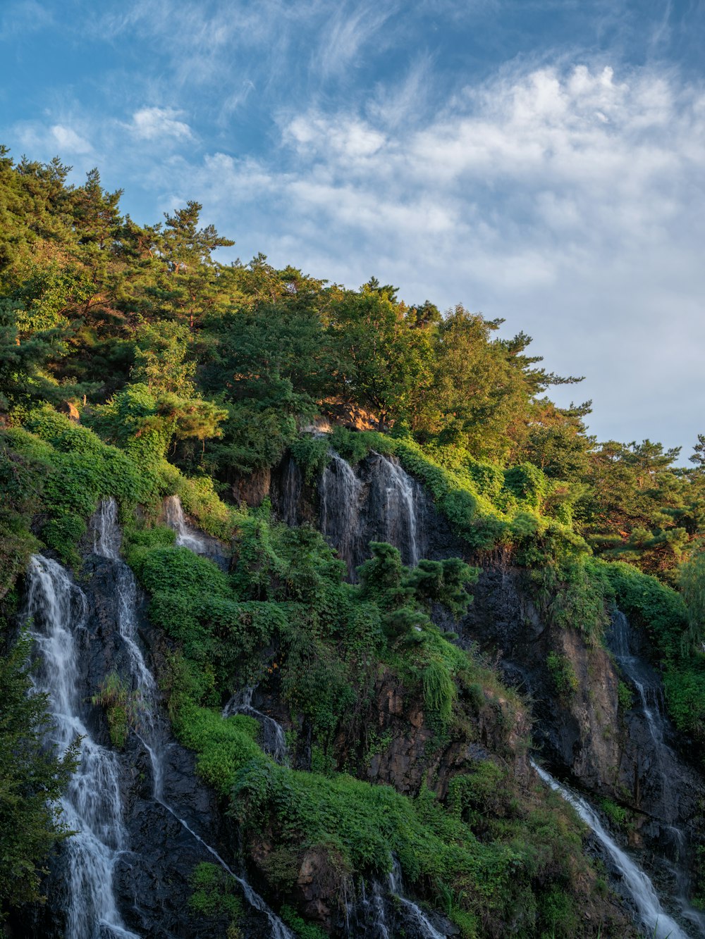 a very tall waterfall next to a lush green forest
