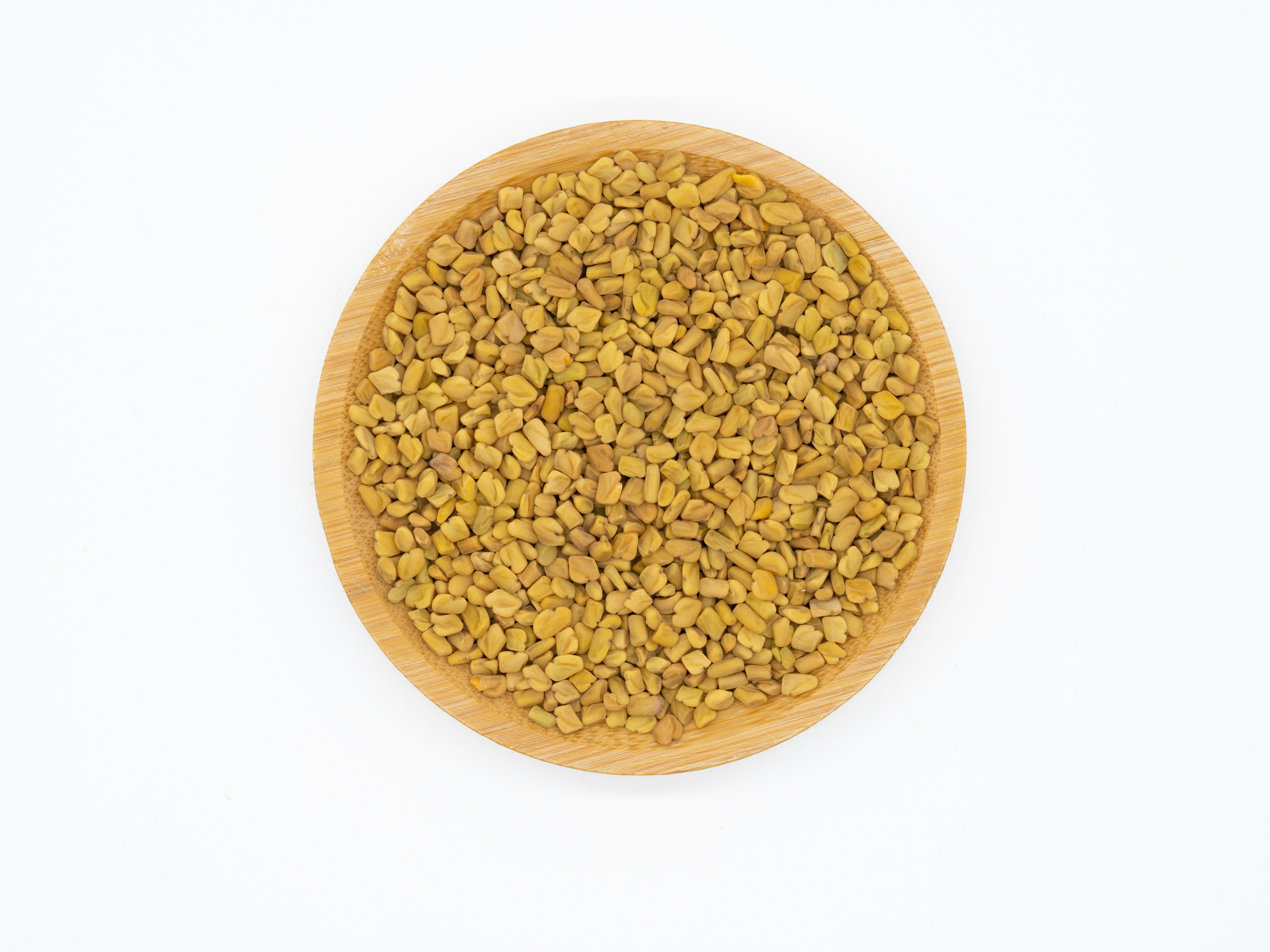 Fenugreek seeds in wooden bowl showing small golden-yellow seeds with distinctive aroma