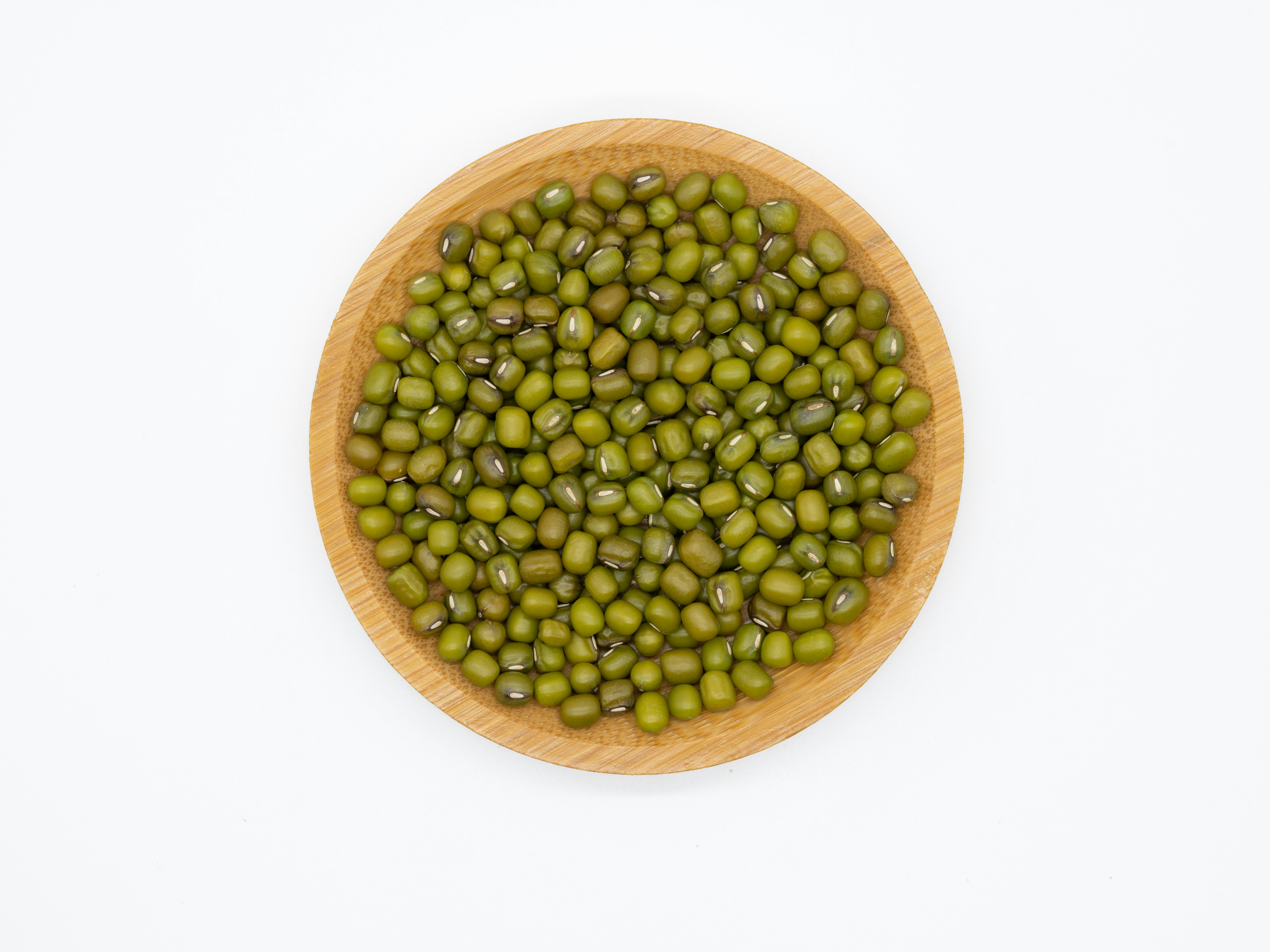 Green mung beans in a rustic ceramic bowl on natural linen surface