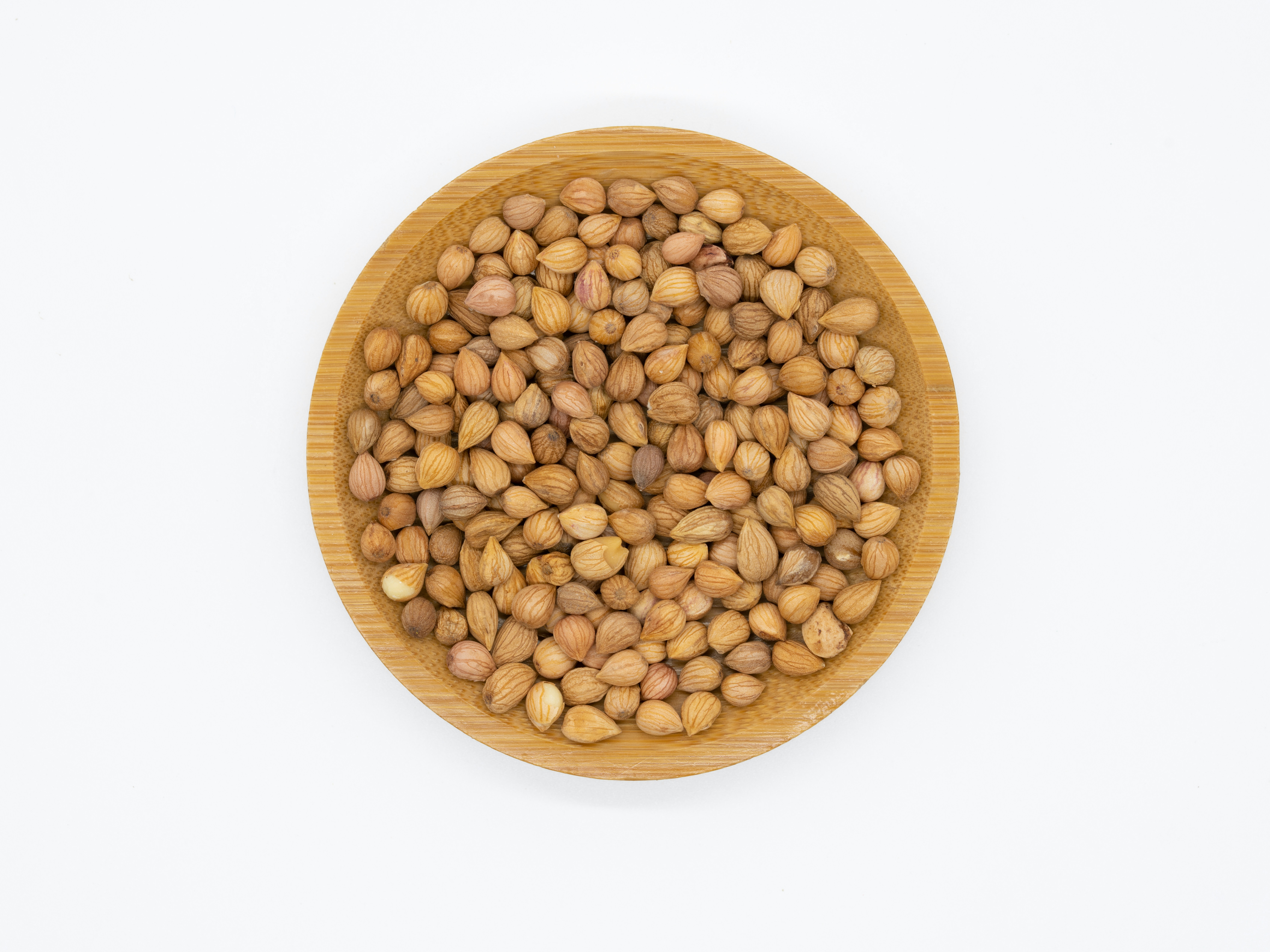 Coriander seeds in bowl with fresh coriander leaves on wooden background