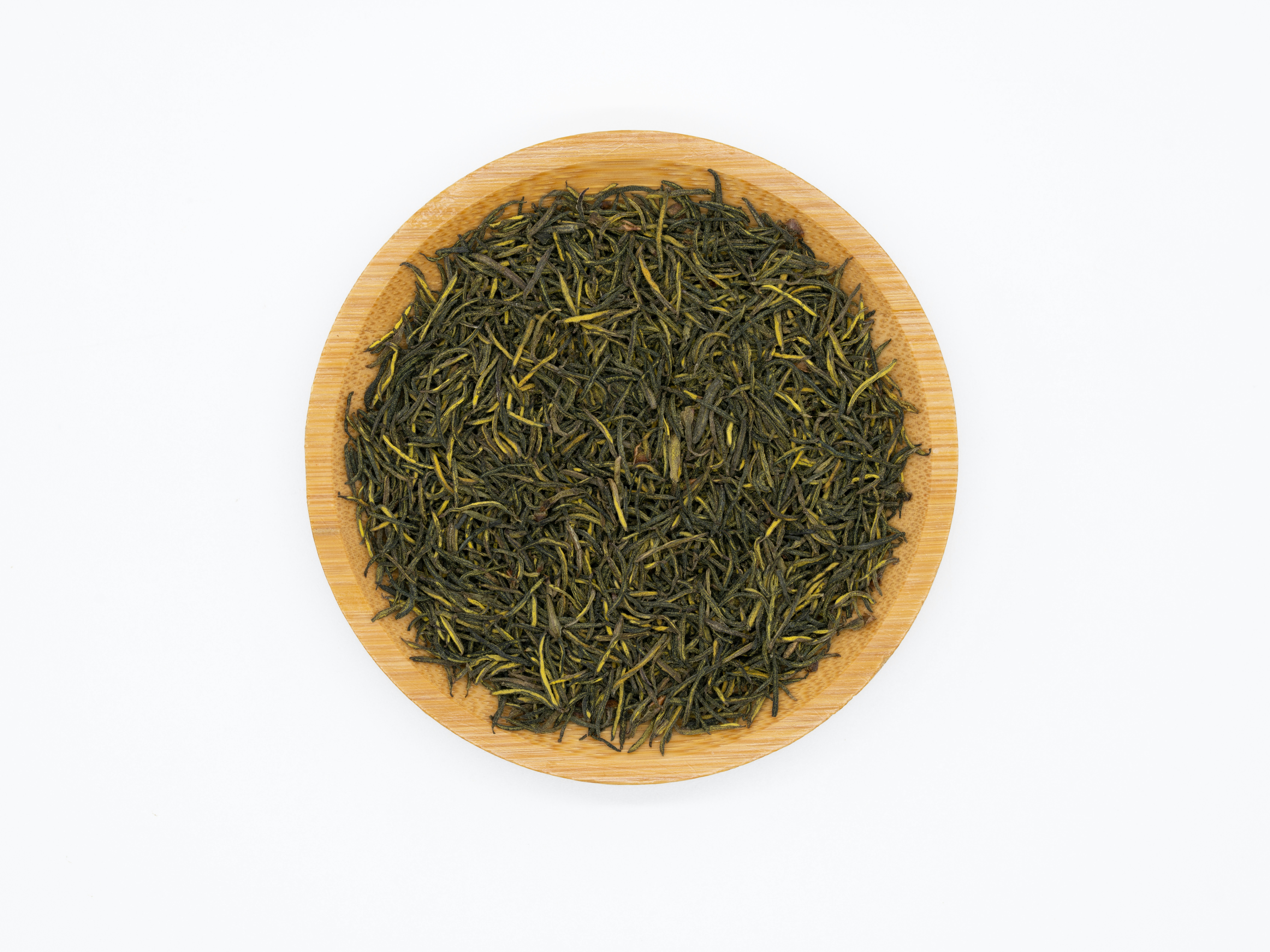 Premium green tea leaves in wooden bowl with warm morning light