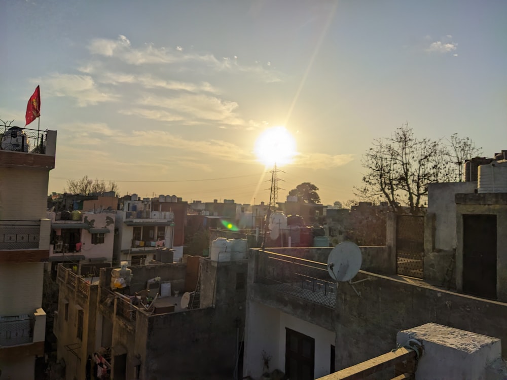 the sun is setting over the rooftops of a city
