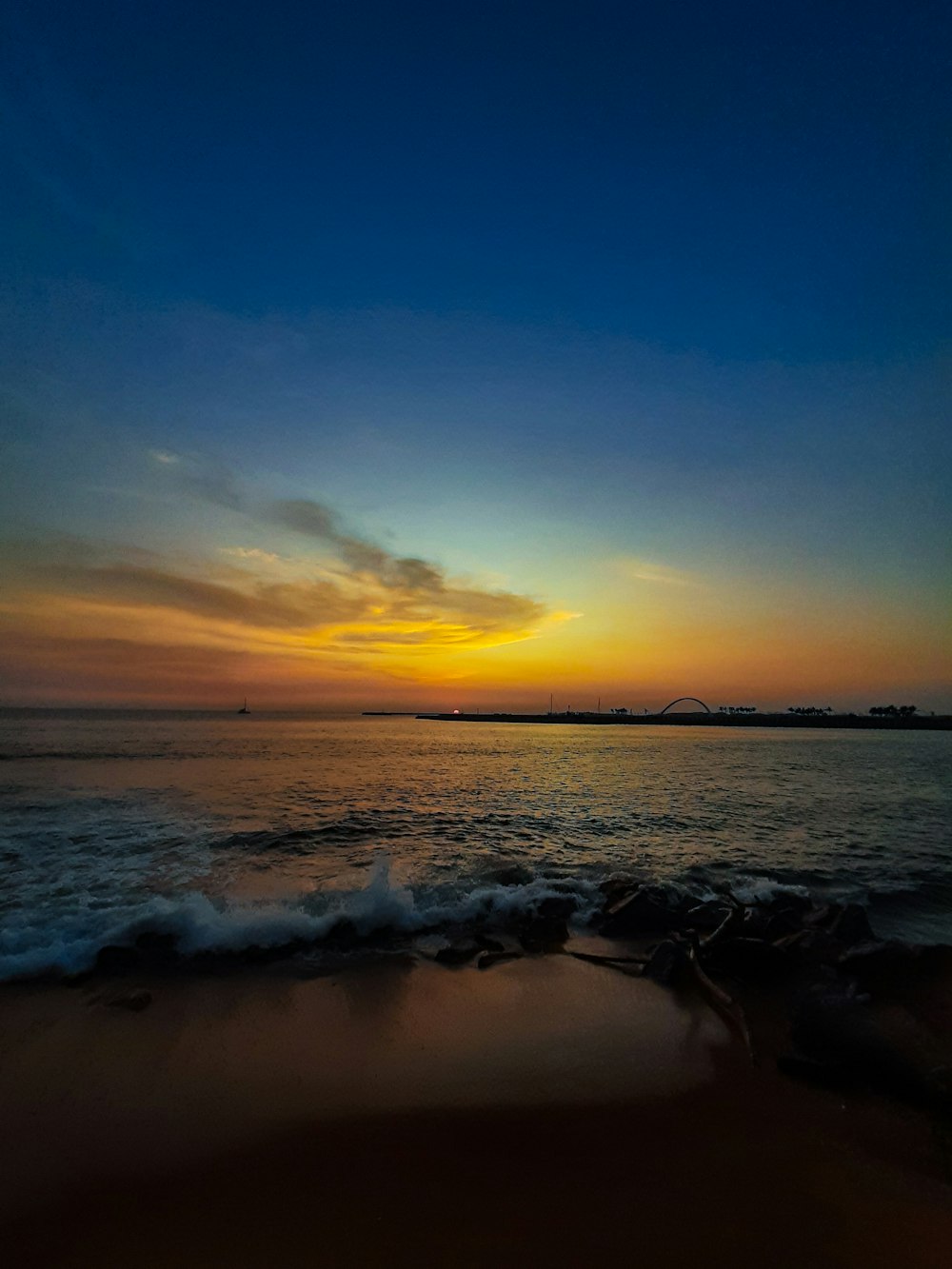 the sun is setting over the water at the beach