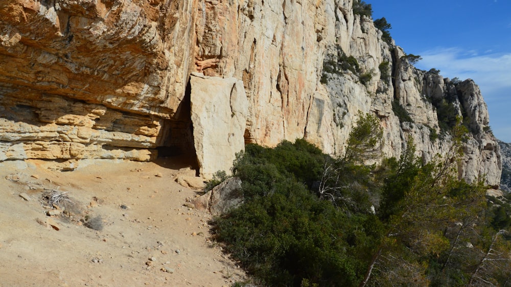 a rocky cliff with a small cave in the middle of it