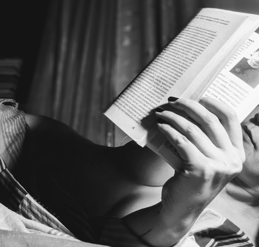 a woman laying in bed reading a book