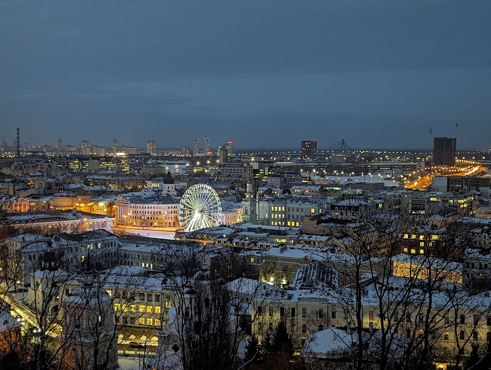 Una veduta di una città di notte con una ruota panoramica in primo piano