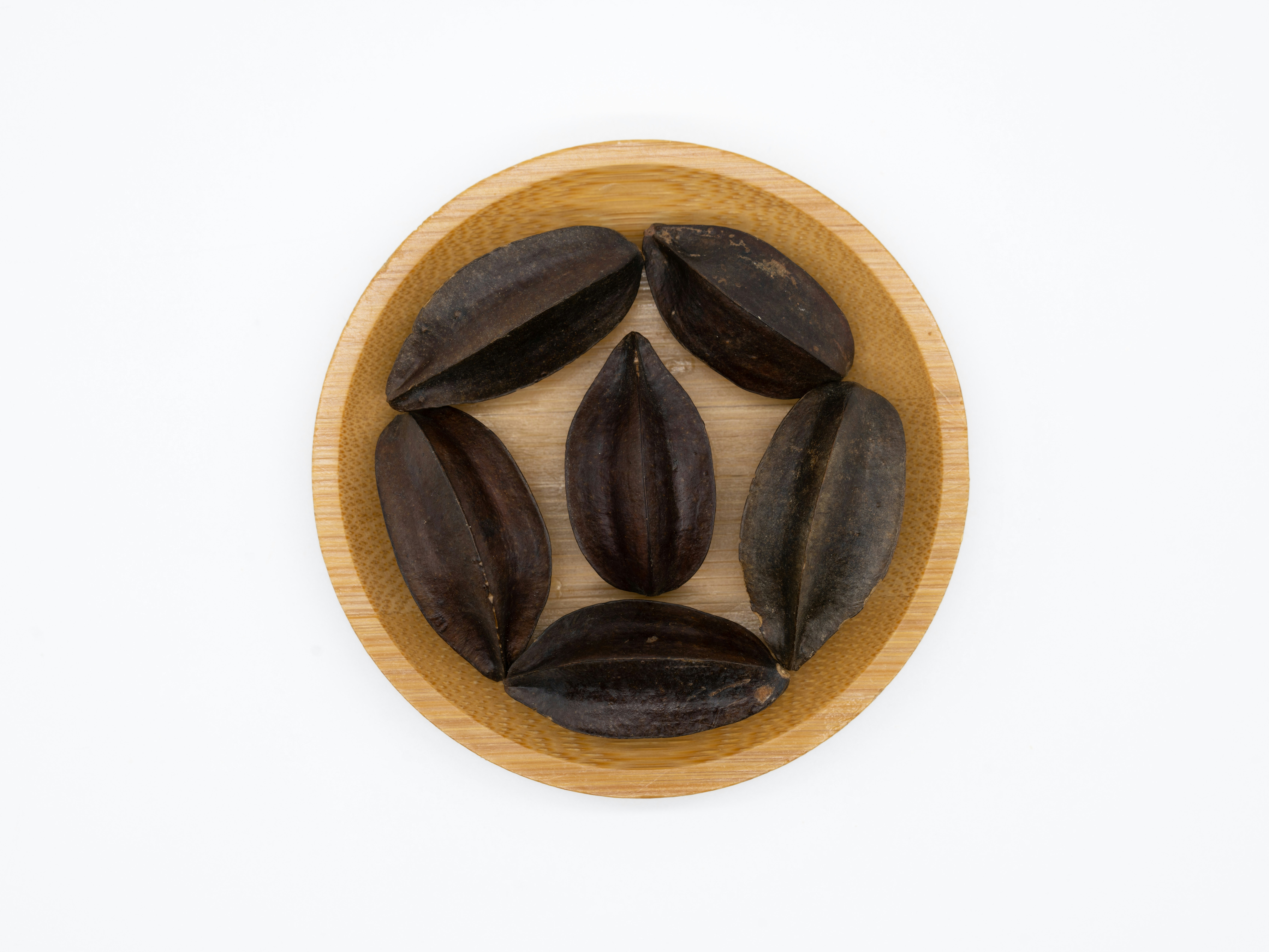 Geometric star anise pods arranged symmetrically on a deep charcoal stone surface with dramatic shadows