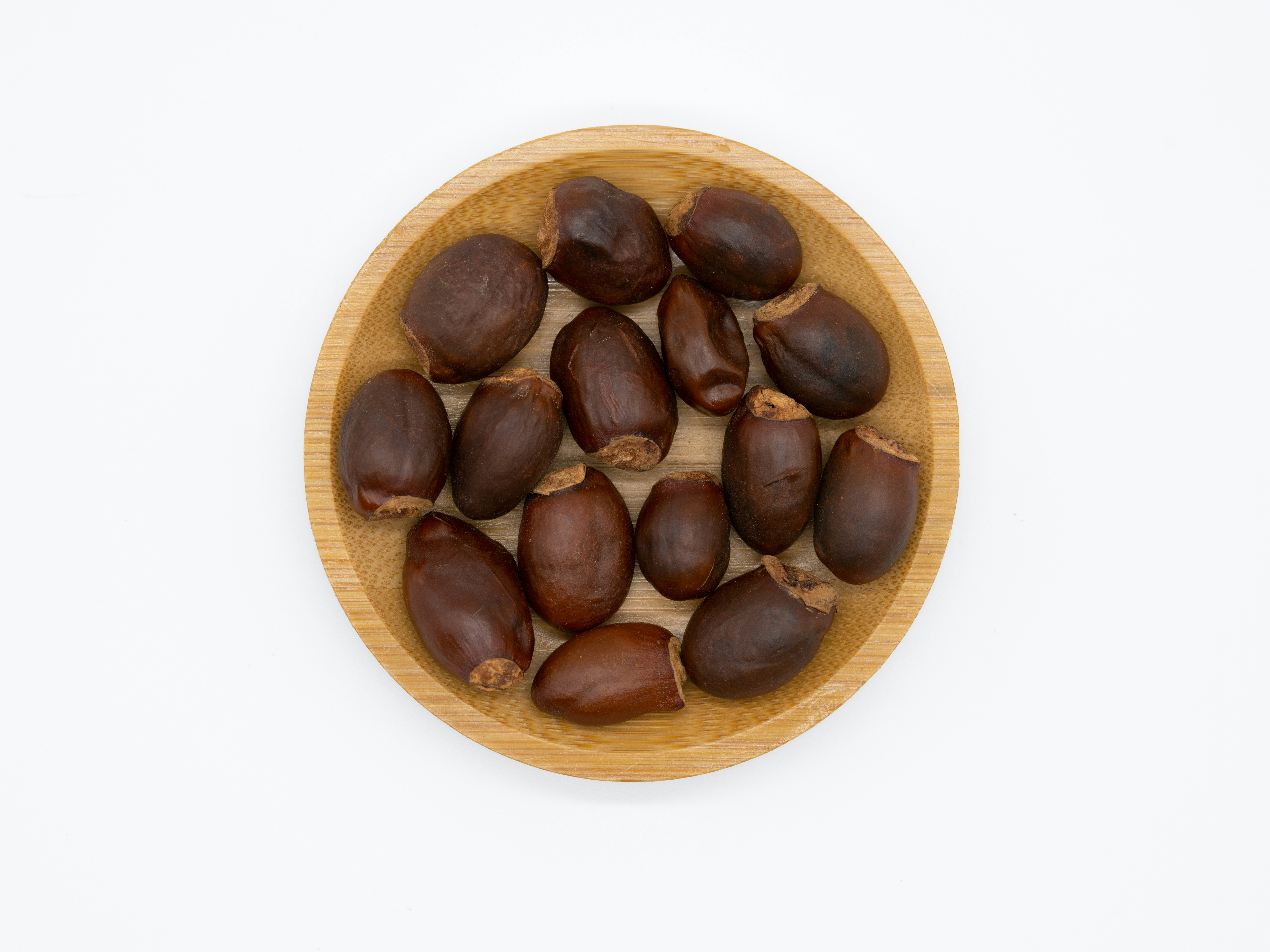 Cluster of earthy brown seeds on dark wooden background, dramatic side lighting, spiritual mood